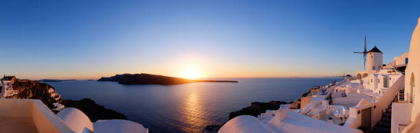 traditionelle apartments und windmühlen in oia dorf bei sonnenuntergang, panoramabild - santorini greece oia sunset stock-fotos und bilder