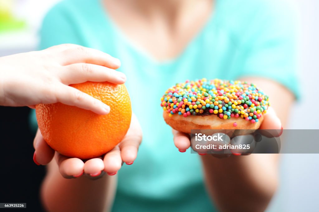 Educate children to choose healthy food concept with little girl choice to eat fruit, not a donut Healthy Eating Stock Photo