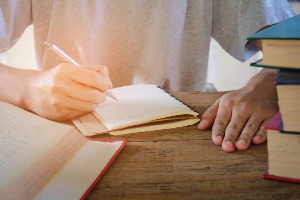 istock Man writing pen in book on old wood 663937026