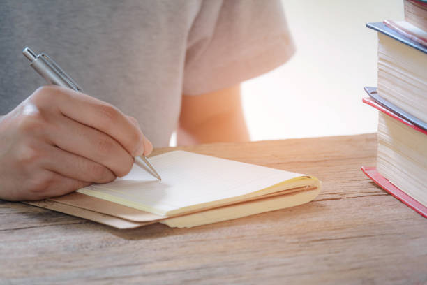 istock Man writing pen in book on old wood 663937126