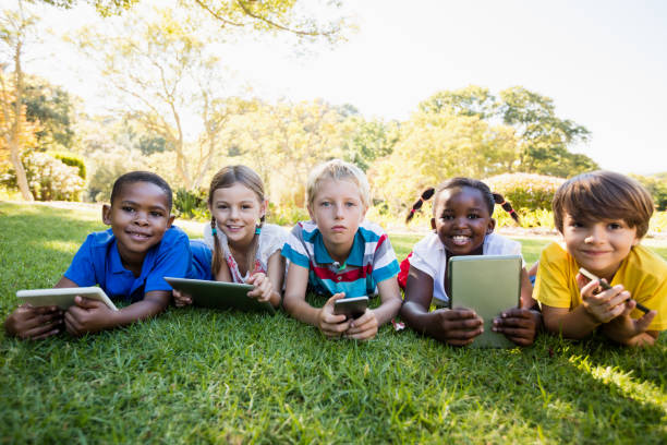 les enfants utilisant la technologie pendant une journée ensoleillée - natural phenomenon affectionate looking at camera outdoors photos et images de collection