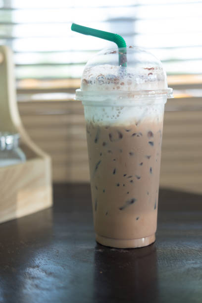 istock Ice chocolate in takeaway cup on wood table with blurred coffee cafe background, Selective focus 663955478
