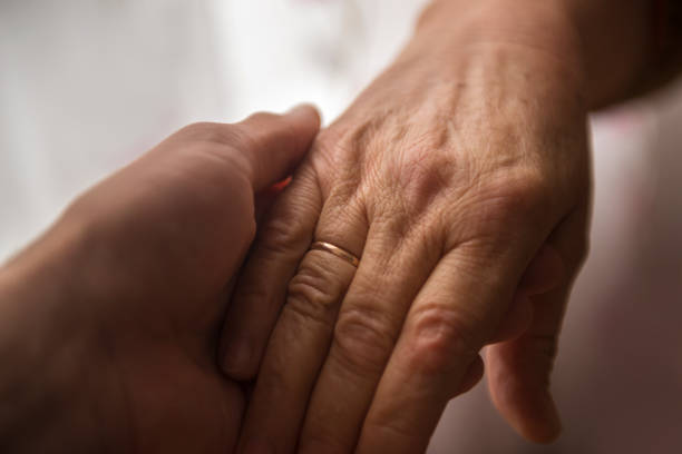 istock High angle view of young man holding senior woman's hand 663958458