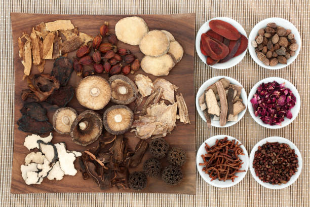 Chinese Medicinal Herbs Chinese herb selection used in natural herbal medicine on maple wood board and in porcelain on bamboo background. spider flower stock pictures, royalty-free photos & images