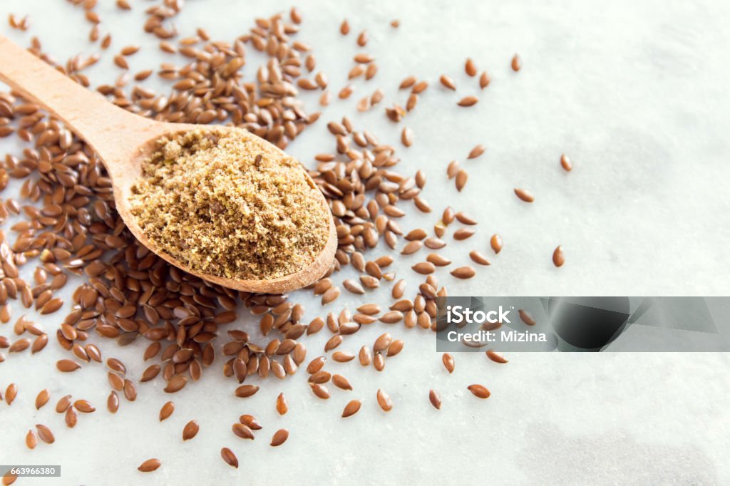 Crushed flax seeds Crushed flax seeds (ground linseed) on wooden spoon and white stone table - healthy organic vegan vegetarian food ingredient Flax Seed Stock Photo