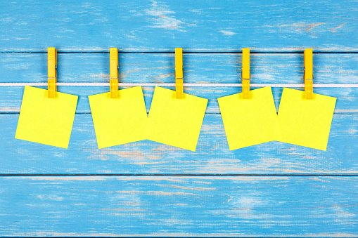 View of five yellow clothespins hanging on a rope with five cards on a blue background