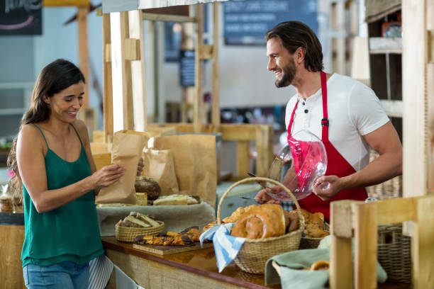 istock Smiling female customer receiving a parcel from bakery staff at counter 663966764