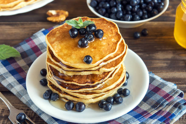 Pancakes on plate with blueberries and honey for family breakfast - homemade healthy vegetarian food