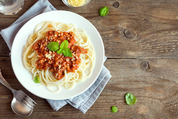Spaghetti bolognese pasta Spaghetti bolognese pasta with tomato sauce and minced meat, grated parmesan cheese and fresh basil - homemade healthy italian pasta on rustic wooden background bolognese sauce photos stock pictures, royalty-free photos & images