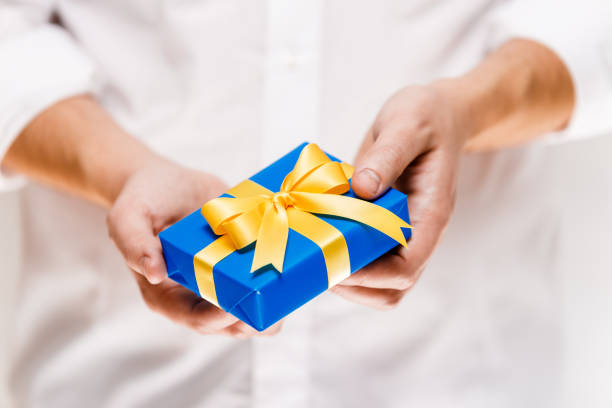 istock Male hands holding a blue gift box with ribbon. 663971140