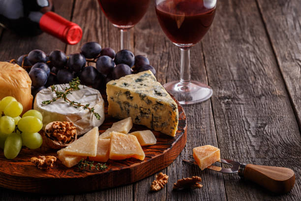 istock Cheese, nuts, grapes and red wine on wooden background 663977942