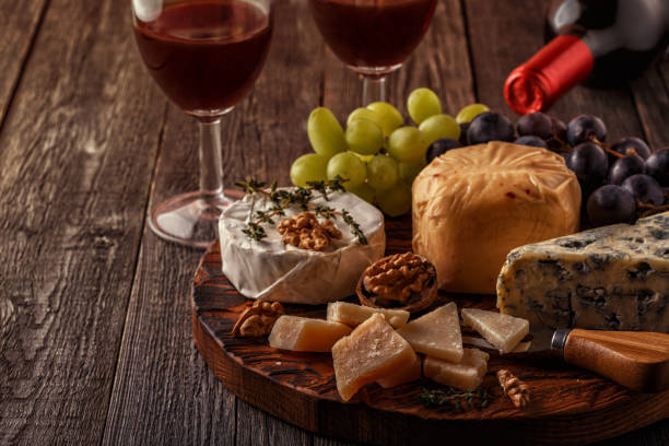 istock Cheese, nuts, grapes and red wine on wooden background 663977950
