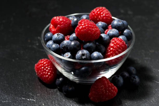 istock fresh berries in a glass bowl on black background 663985236
