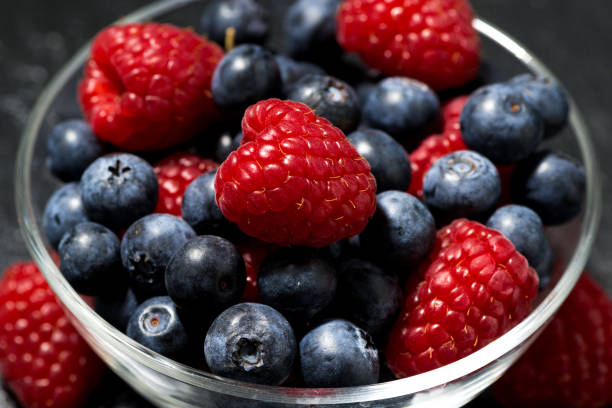 istock fresh berries in a glass bowl on dark background, closeup 663985390