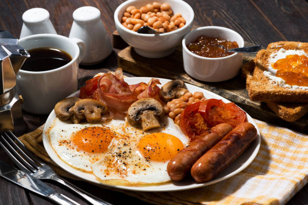 istock Fried eggs with bacon, sausages and vegetables for breakfast 663988454