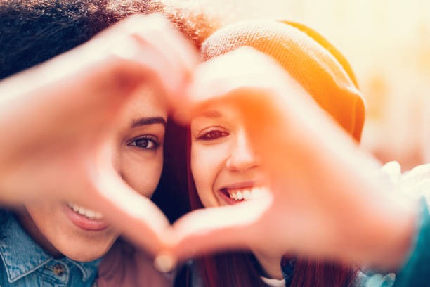 istock Mixed race girls making heart symbol with hands 663988482