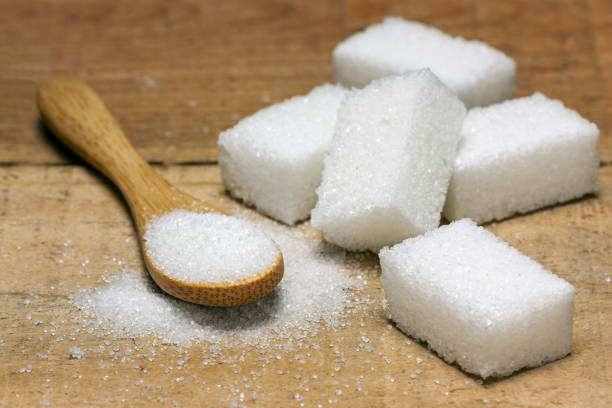 istock sugar cube in the spoon on wood background 663993766