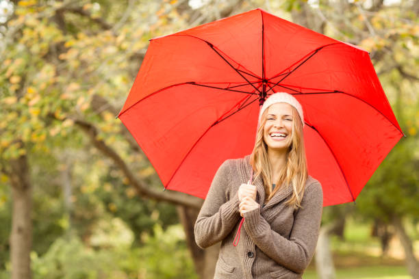 istock Smiling young woman under umbrella 663994434
