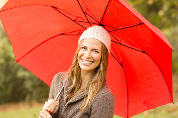 istock Smiling young woman under umbrella 663994510