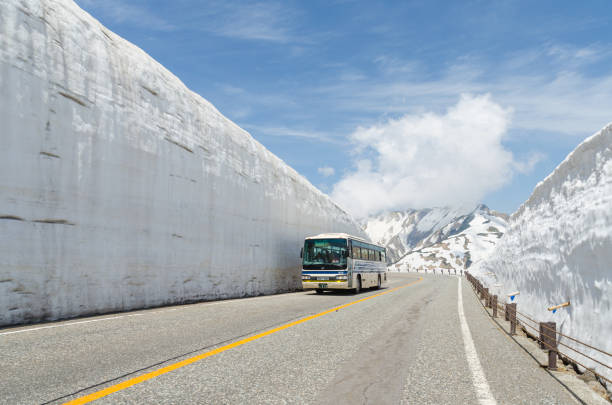 bus verplaats langs sneeuw muur op tateyama kurobe alpine - hida bergketen stockfoto's en -beelden