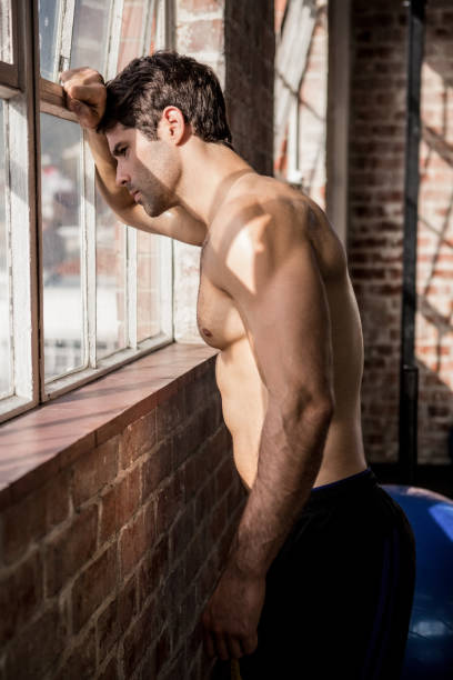 istock Shirtless man looking outside from window 663997494