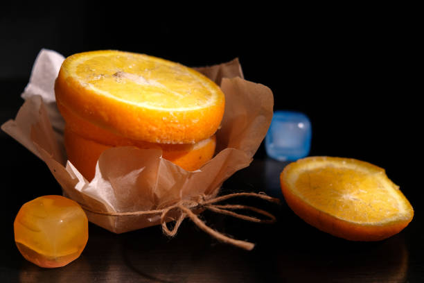 istock frozen fresh orange on black table sliced and stacked on one another stand on paper wrapper except top which lay near on surface and add two plastic ice cube lighting by spot with more depth of field 664000190