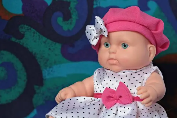 Little doll in a beret with a bow in polka dots