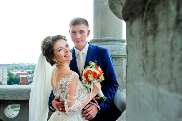 istock Wedding couple looking at the camera on stone balcony 664007298