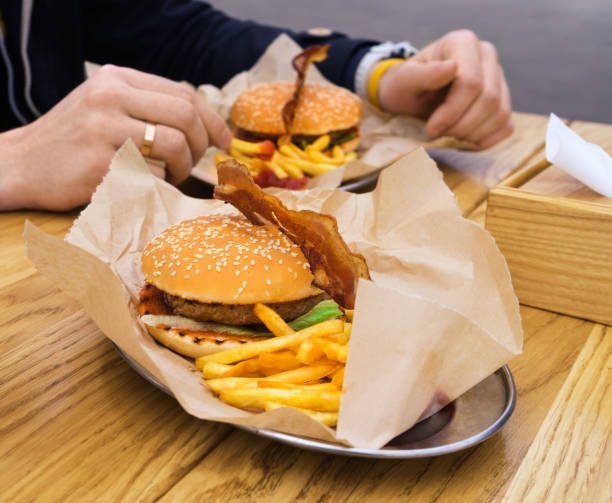 istock Man eating burger with bacon with fried potatoes 664010524