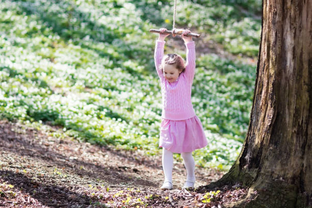 istock Child swinging on tree rope swing 664011050