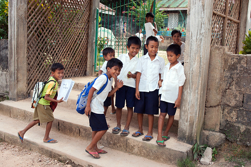 Popototan Island, Philippines - January 16,2012: Funny children run to school in a Filipino village