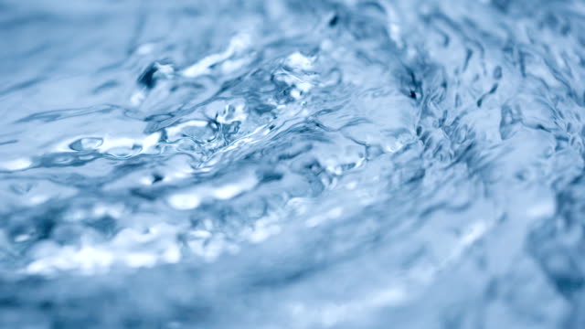 Water flow abstract. Real video, slow motion, blue frozen surface, abstract background. Macro shot.