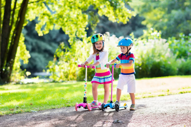 kids riding scooter in summer park. - 11321 imagens e fotografias de stock