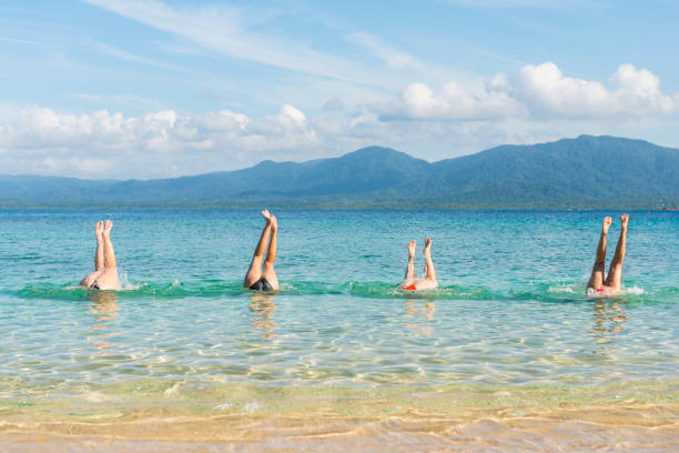 istock Four women handstand in turquoise sea 664046230