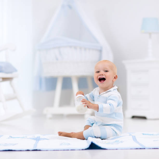 istock Baby boy drinking milk in sunny nursery 664046406
