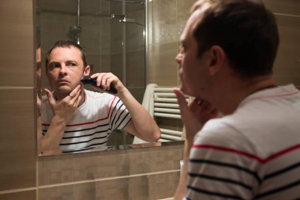 istock Handsome man shaving in the mirror in the bathroom 664055632
