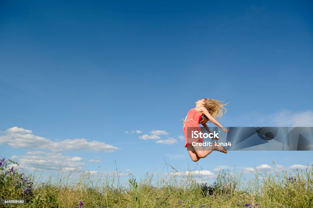 happy woman leaping Frau macht Freudensprungjoyful young blond woman leaping Adult Stock Photo