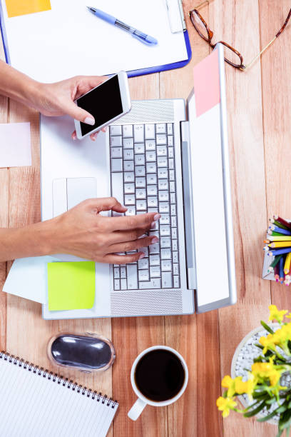 istock Overhead of feminine hands using laptop and smartphone 664078310