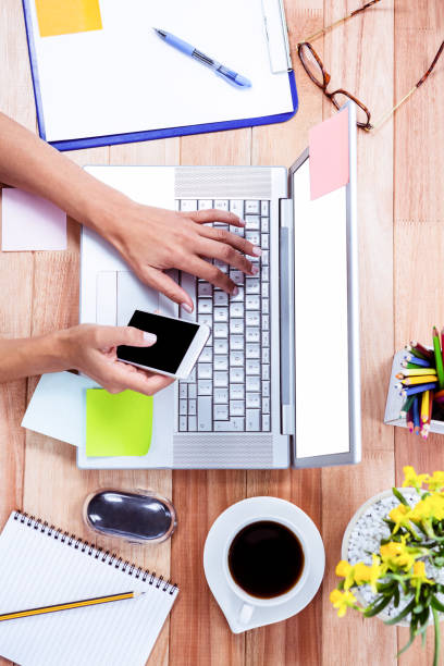istock Overhead of feminine hands using laptop and smartphone 664078362