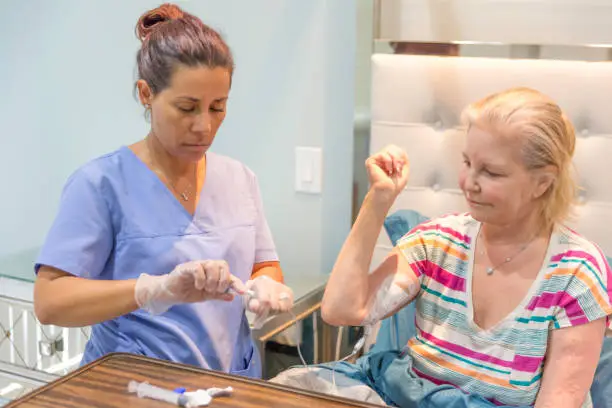 Photo of Home healthcare nurse flushing picc line of recovering patient