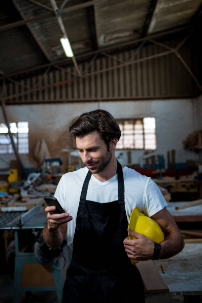 istock Carpenter texting someone and holding his helmet 664087904