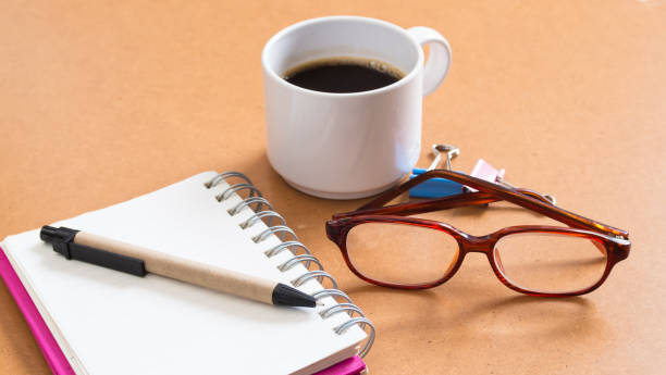 istock blank open notebook on a brown table with a cup of coffee and eye glasses 664098998