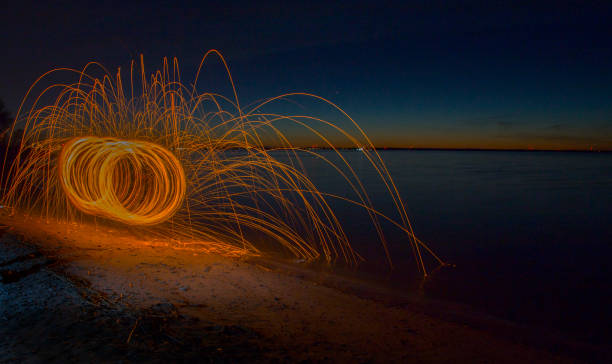 istock Fire sparks flying through the air at sunset along the lake shore 664109594