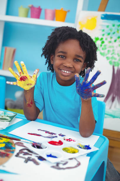 istock Happy kid enjoying painting with his hands 664113184