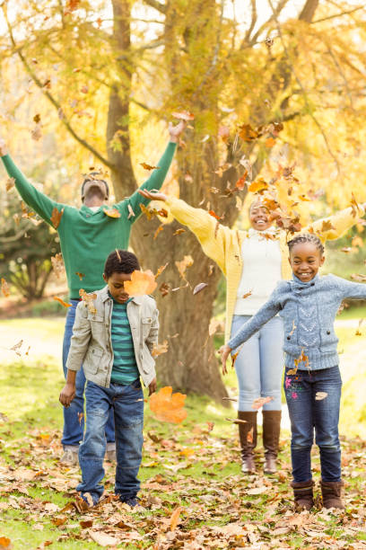 istock Young smiling family throwing leaves around 664128406