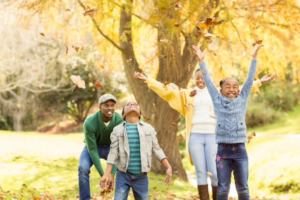 istock Young smiling family throwing leaves around 664128432