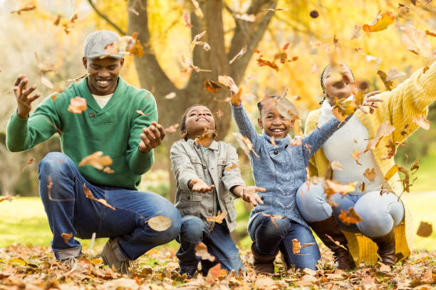 istock Young smiling family throwing leaves around 664128674