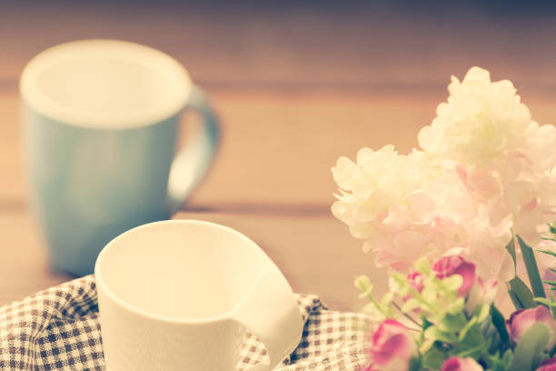Blue and white coffee cups on wood table with flower bouquet decoration background,retro filter image