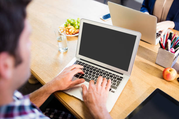 Free Stock Photo of A man sitting at a desk with a laptop in front of ...