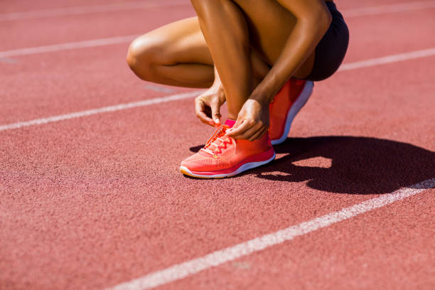 istock Female athlete tying her shoe laces on running track 664174552